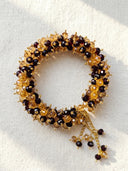 Decorative wreath with gold, black, and brown beads on a white background