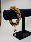 Gold bracelet with gemstones on a black velvet stand